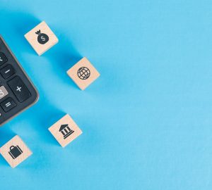 Conceito financeiro com ícones em cubos de madeira, calculadora na tabela azul plana leigos