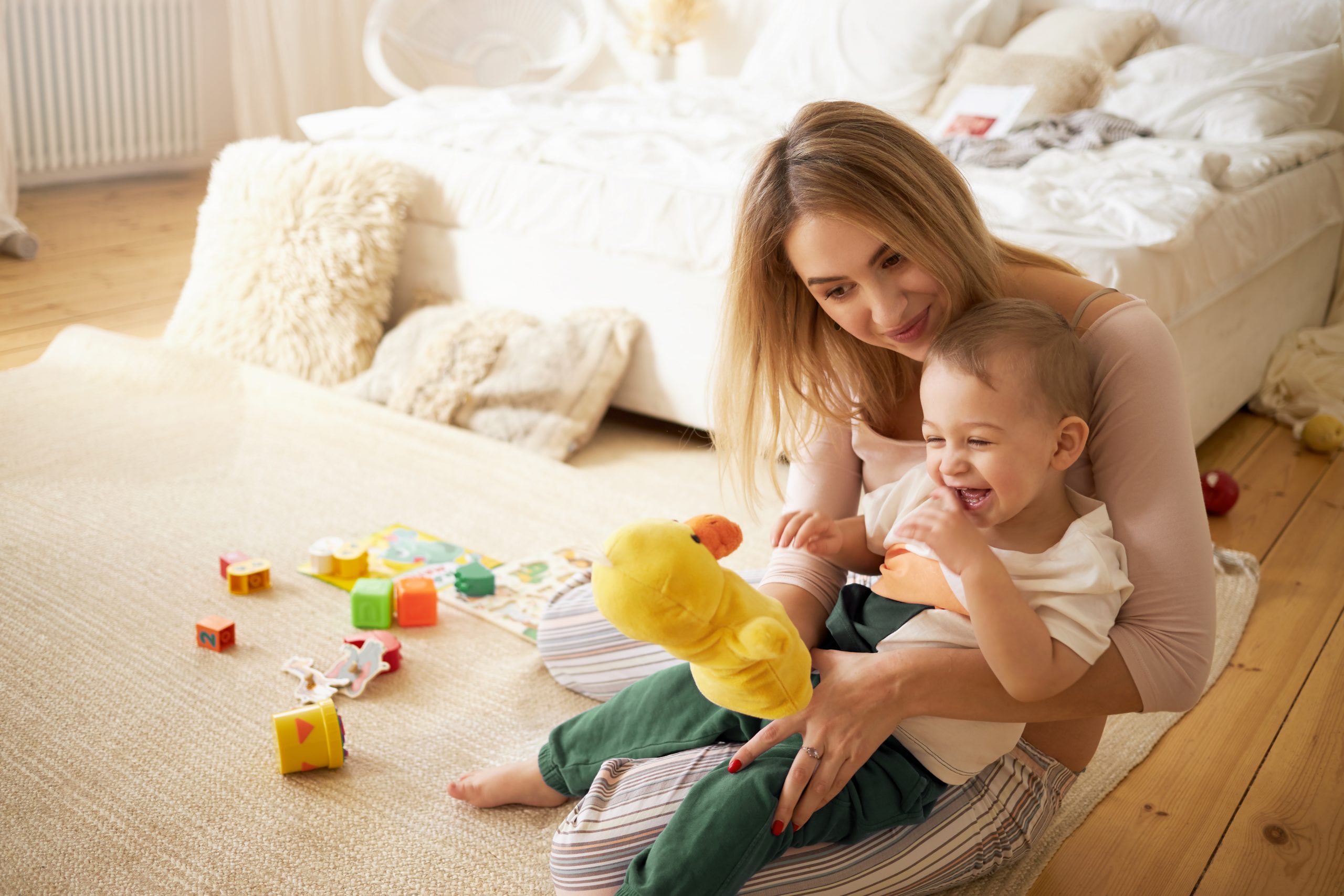 mãe com bebê brincando no chão do quarto, simbolizando o pagamento do salário-maternidade